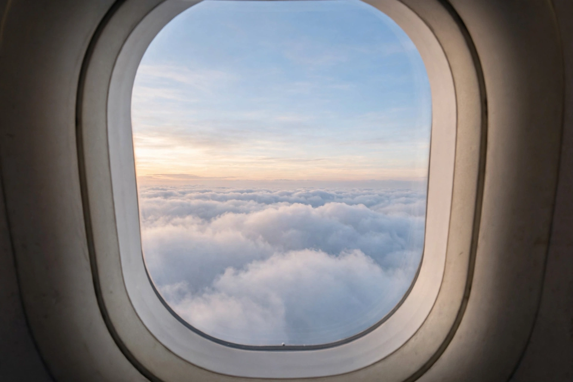 Calm view above soft clouds at dawn through an airplane window, symbolising calmer flying with diazepam guidance